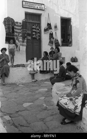 Griechenland, Grecia - Frauen und Kinder sitzen vor einem Andenkenladen in einer Gasse nahe de antiken Mykene in Griechenland, 1950er Jahre. Donne e bambini seduti davanti a un negozio di souvenir in un piccolo vicolo vicino alla antica Micene in Grecia, 1950s. Foto Stock