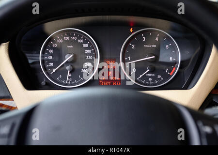 Pannello multifunzionale di auto di lusso con tachimetro tachimetro indicatori e parte del volante fuori fuoco closeup. Foto Stock