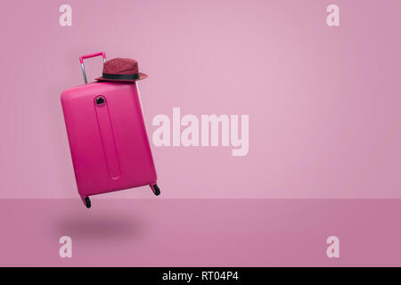 Valigia rosa con hat sul rosa pastello sfondo. concetto di viaggio. Stile minimal. Foto Stock
