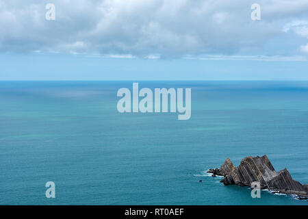Seascape di blu oceano mare acqua con cielo coperto. Ripida rupe robusto penisola di roccia in corrispondenza del bordo della calma oceano. Foto Stock