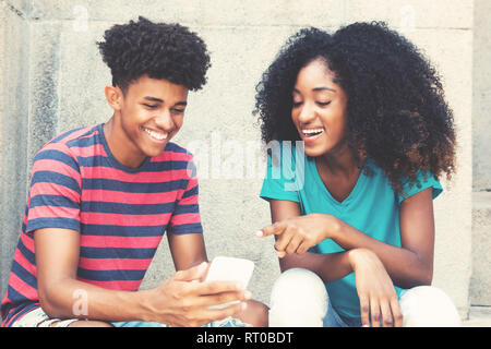 African American giovane adulto hipster uomo mostrando le immagini al telefono all'aperto in vintage look rétro Foto Stock