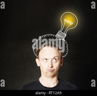 Idea concetto. Uomo di pensiero sulla lavagna sfondo con lampadina. Brainstorm e idea Foto Stock