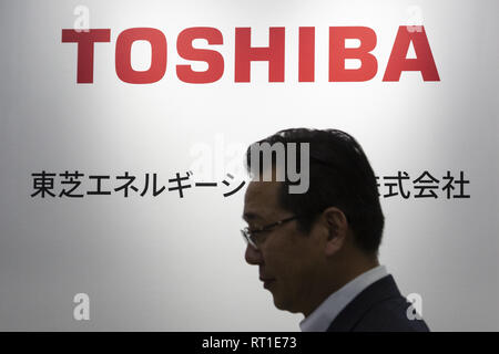 Tokyo, Giappone. Il 27 febbraio, 2019. Un uomo cammina passato un logo Toshiba Corp. durante la batteria mostra il Giappone a Tokyo Big Sight. In mostra le più recenti tecnologie connesse alla batteria ricaricabile prodotti durante i tre giorni di fiera a Tokyo Big Sight. Credito: Rodrigo Reyes Marin/ZUMA filo/Alamy Live News Foto Stock