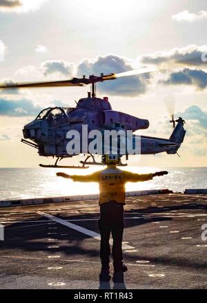 190221-N-HG389-0080 mare mediterraneo (feb. 21, 2019) di aviazione di Boatswain Mate (movimentazione) terza classe Kenneth Smith segnali ad un AH-1W Super elicottero Cobra assegnato al "Cavalieri Neri" del mezzo marino Tiltrotor Squadron (VMM) 264 (rinforzato) come si atterra sul ponte di volo del San Antonio-classe di trasporto anfibio dock nave USS Arlington (24 LPD), feb 21, 2019. Arlington è su una distribuzione programmata come parte dell'anfibio Kearsarge Gruppo pronto a sostegno della sicurezza marittima, operazioni di risposta alle crisi del teatro e la cooperazione in materia di sicurezza, fornendo nel contempo anche un avanzamento presenti navale Foto Stock