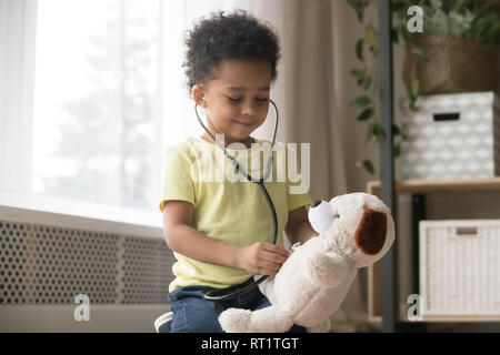 Carino il ragazzo africano giocando con il giocattolo come medico tenendo uno stetoscopio Foto Stock