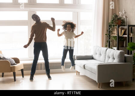 Funny african padre e figlia di capretto ridere jumping a casa Foto Stock