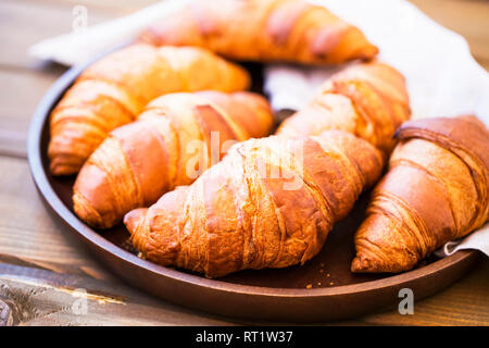 Freschi panini croisssants mucchio nel vassoio in legno, francese cornetti freschi croccanti croissant panini Foto Stock