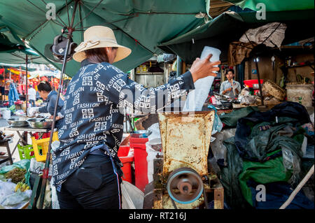 Una signora cambogiana usa un frantoio di ghiaccio nel mercato centrale Phnom Penh Cambogia. Foto Stock