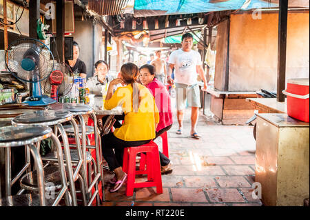 Gli amici si gustano un pranzo in un negozio di noodle del mercato in un affollato mercato interno a Phnom Penh, Cambogia. Foto Stock