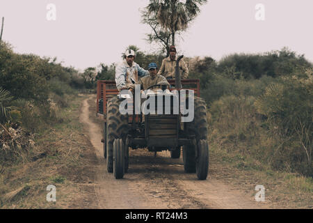 Tre i lavoratori agricoli la guida grande vecchio trattore su strada polverosa in campagna, provincia di Formosa, Argentina del nord Foto Stock