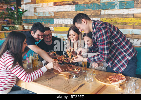 Felice gli amici condividono la pizza al pub rustico Foto Stock