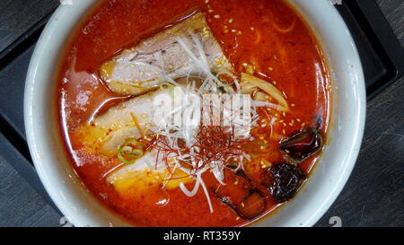 La tirata a mano tesa cinese di spaghetti ramen su una ciotola con baguette Foto Stock