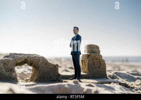 Imprenditore figurina permanente sulla sabbia da edifici di sabbia Foto Stock