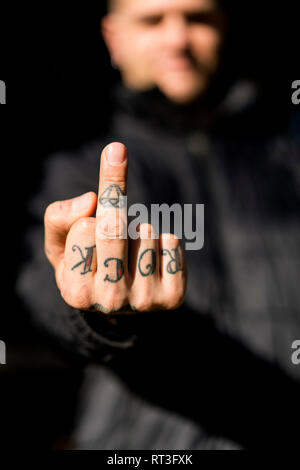 Tatuato uomo dando il dito, close-up Foto Stock