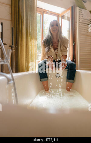 Ritratto di ridere donna seduta sul davanzale della finestra in bagno gli schizzi con acqua Foto Stock