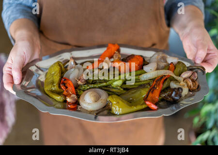 Mani tenendo la piastra con verdure fritte Foto Stock