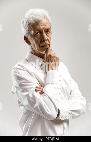Imprenditore gravi isolato su grigio di sfondo per studio. Metà maschio-lunghezza verticale. Le emozioni umane, espressione facciale concept Foto Stock