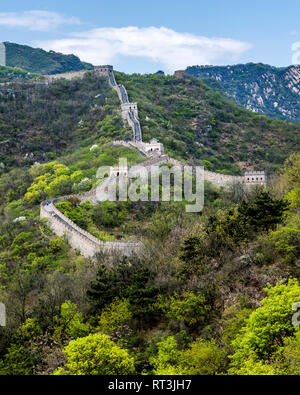 I turisti escursione lungo la Grande Muraglia a Mutianyu. Numerose torri di avvistamento può essere visto come la parete si inerpica su per la montagna attraverso il fitto bosco. Foto Stock