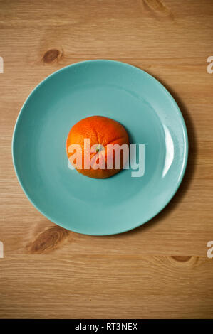 Mezza arancia frutto su una acquamarina piastra blu Foto Stock