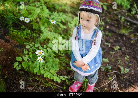 Ritratto di triste bambina indossa berretto lavorato a maglia e denim dress all'aperto Foto Stock