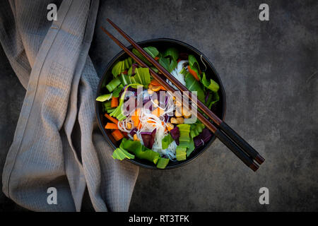 Ciotola di vetro a base di noodle con insalata di verdure e arachidi Foto Stock