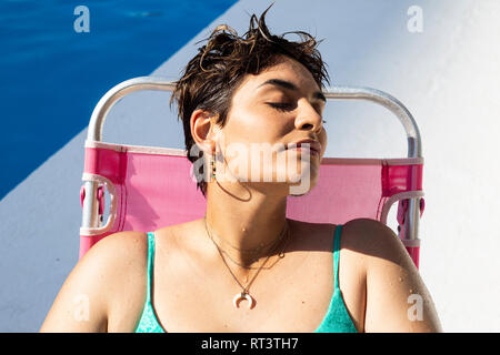 Ritratto di giovane donna relax sulle sdraio in piscina Foto Stock