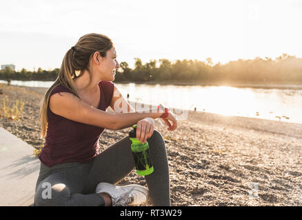 Giovane donna prendendo una pausa dopo aver esercitato sul fiume Foto Stock