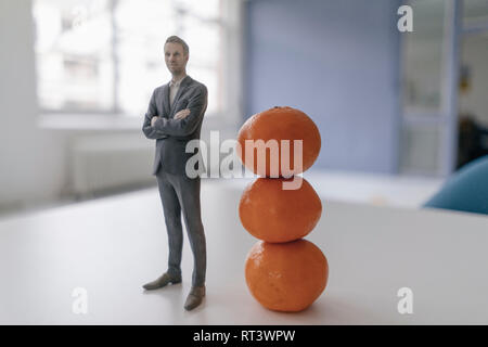 Imprenditore in miniatura statuetta in piedi accanto alle clementine Foto Stock