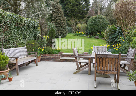 Panca in legno, tavolo e sedie sul patio in una Londra giardino suburbano Foto Stock