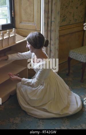 La Principessa Victoria gioca con le sue bambole casa a una finestra nella sua camera da letto a Kensington Palace. Indossa un abito bianco e ha i suoi capelli in un panino. Foto Stock