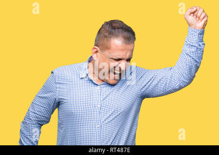 Età media arab business man su sfondo isolato Dancing felice e allegro e sorridente spostamento casuale e di ascolto fiducioso della musica Foto Stock