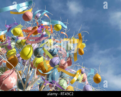 Le uova di pasqua contro il cielo blu con nuvole bianche. Struttura di festa con decorazioni di pasqua e nastri colorati, sfondo per biglietto di auguri Foto Stock