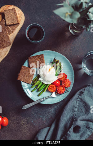 Vista da sopra sulla cena per uno, Uovo affogato sul grill e asparagi pomodori ciliegia. Foto Stock