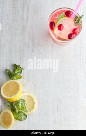 Dissetante bevanda estiva con berry e limone sulla luce di un tavolo di legno. Il concetto di estate bevande con ghiaccio. vetro con summer cocktail con Foto Stock