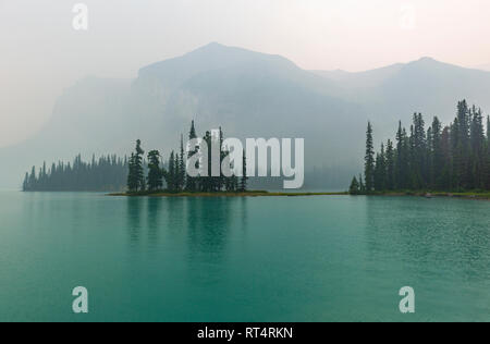 La riflessione dell'inafferrabile e magnifica isola di spirito nella nebbia, situato all'interno del Lago Maligne nel Parco Nazionale di Jasper, Alberta, Canada. Foto Stock