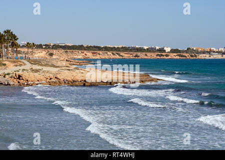 Costa rocciosa del Flamenco beach in Orihuela Costa. Surf Mar Mediterraneo, inverno clima tropicale giornata di sole. Provincia di Alicante, Costa Blanca, Sp Foto Stock