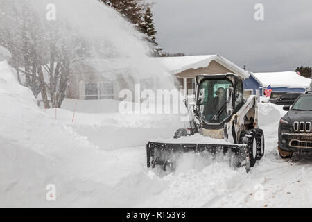 Grand Marais, Michigan - un industriale lo spalaneve cancella la neve da una strada in una città sul lago Superiore nella Penisola Superiore del Michigan.. La città averag Foto Stock