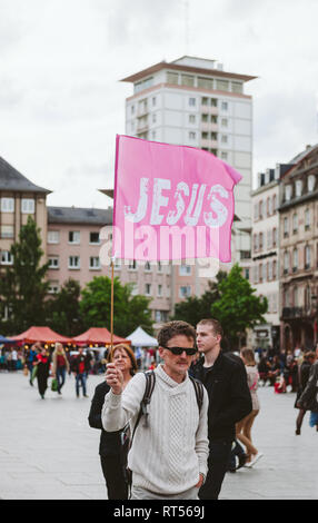 Strasburgo, Francia - 30 Maggio 2015: l'uomo con il rosa Gesù bandiera a marzo per Gesù l'annuale evento interconfessionale dai cristiani di tutto il mondo Foto Stock