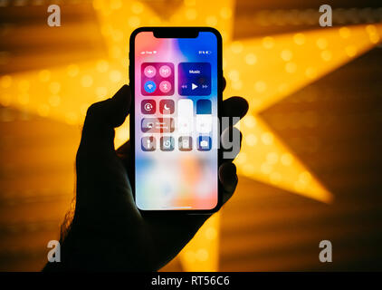 Parigi, Francia - Nov 10, 2017: uomo tenendo il nuovo Apple iPhone X 10 Display con stella gialla sfondo bokeh di fondo dotato di centro di controllo pulsanti Foto Stock