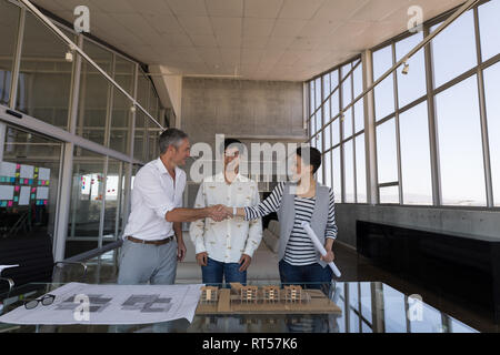 Colleghi di lavoro discutendo su blueprint in office Foto Stock