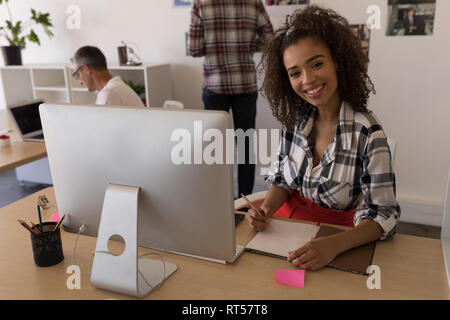 Executive femmina la scrittura sul diario alla scrivania Foto Stock