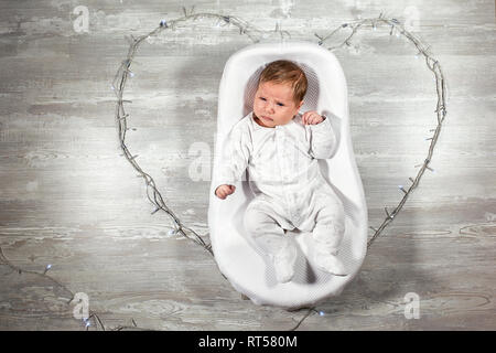 Il neonato dorme tranquillamente in una speciale materasso ortopedico Baby cocoon, su un pavimento di legno. La calma e il sonno sano nei neonati. Foto Stock