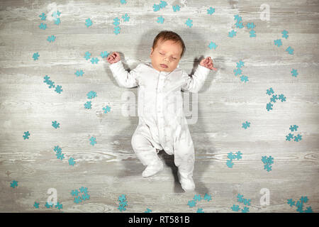 Il neonato dorme tranquillamente su un pavimento di legno puzzle blu intorno a. Calma e dormire in modo sano con neonati Foto Stock