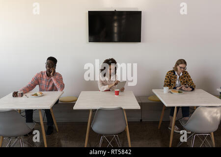 Colleghi di lavoro utilizzando tavoletta digitale e parlando al telefono cellulare in ufficio Foto Stock
