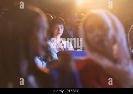 Imprenditrice seduta in auditorium e guardando la fotocamera Foto Stock
