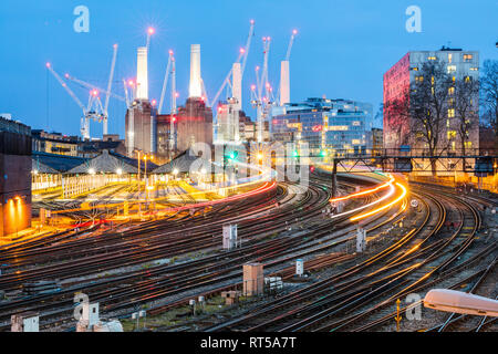 Regno Unito, Inghilterra, Londra, vista di railtracks e treni di sera, ex Battersea Power Station e gru in background Foto Stock