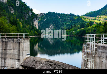 Bella aqua e colori blu del lago Spajici e il fiume Beli Rzav, sulla montagna di Tara Verde, alberi e piccole case di villaggio e dam Foto Stock