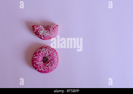 Le ciambelle con la glassa rosa su sfondo color pastello con posto per il testo. Layout creativo fatto di ciambelle rosa. Lay piatto. Concetto di cibo. Stile minimal. Vista dall'alto. Foto Stock