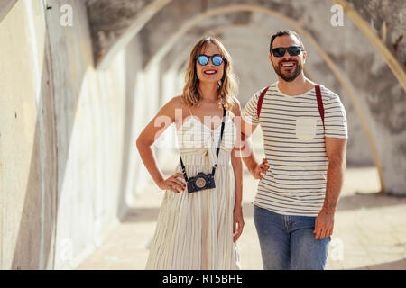 Spagna, Andalusia, Malaga, felice turista giovane in piedi sotto un arco in città Foto Stock