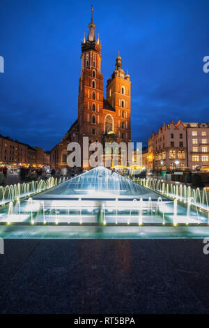 La Polonia, Cracovia, la Città Vecchia di notte illuminata di Chiesa di Santa Maria e la fontana Foto Stock